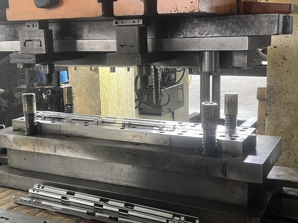 Progressive stamping die producing rail members with punched slots and keyholes